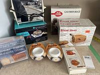 Full lot showing toaster, waffle maker, bread keeper, poachers, and bread slicer in box