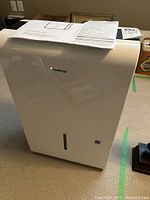 Front view of Kool King dehumidifier with instruction manuals placed on top.