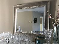 Front view of rectangular wall mirror showing silver textured frame and clear reflective glass.