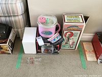 Full view showing the pink ice creamer and original box of Hamilton Beach Drink Master shake maker with promotional items and packaging.
