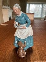 Front view of the Royal Doulton porcelain figurine showing the woman holding a plate and jug with a cat at her feet.
