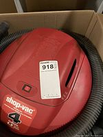 Top view of red Shop-Vac wet/dry vacuum with hose attached, showing 4 gallon capacity label.