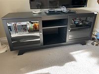 Front view of black TV stand with glass doors and center shelves