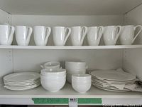 Photo showing 8 white ceramic mugs on a top shelf, with a textured leafy design.