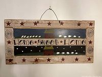 Front view of the wooden wall art plaque painted with 'Home Sweet Home' text, bird, star, and house motifs