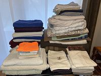 Full view of multiple folded linens including blankets, sheets, pillowcases, towels stacked in piles