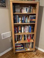 Front view of wood bookcase filled with books and some CDs to show shelf structure and size.