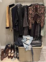 Overview of hanging clothing, shoes on floor and tote with items