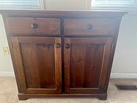 Front view of wood dresser showing two drawers and cabinet doors with round knobs.
