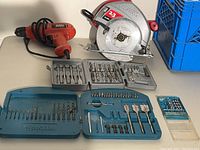 Full lot photo showing the Skilsaw circular saw, Black & Decker drill, and three sets of drill bits and drivers arranged on a surface.