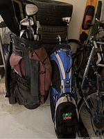 Two golf bags side by side in garage setting, King Cobra clubs and Wilson golf bag.