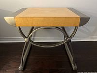 Front view of side table showing wood top with metal edges and curved metal supports.