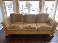 Front view of a three-seat striped sofa with cushion zippers, showing full length and armrests.