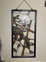 Front view of stained glass panel with grapevine design, showing detailed colors and black metal frame with hanging chain.