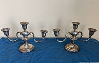 Both candelabras displayed side by side on blue cloth