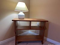 Front view of the wood side table with table lamp on top, showing the table shelves and lamp base.