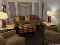 Living room setting with two table lamps sitting on side tables, with couches and ottoman in the background.