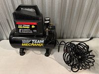 Front right side view showing control panel, pressure gauges, handle, and attached coiled air hose.