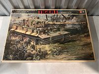 Box cover art for Tamiya German Tiger I tank model kit showing detailed tank and soldiers in combat scene.