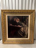 Full frontal image of the large vintage framed painting of a couple drawing together, framed in an ornate gold frame.