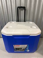 Entire cooler showing blue body, white lid with four cup holders, telescoping handle extended.