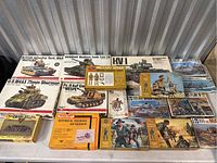 Wide shot of all model kits and figurine boxes on white table against corrugated metal background.