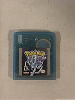 Top-down view of translucent teal Game Boy Color cartridge with Pokemon Crystal Version label featuring Suicune
