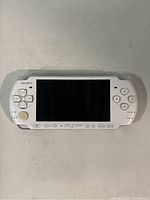 Front view of white Sony PSP 3001 with screen, buttons and directional pad visible.