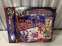 Photo of the back of the WWE Stunt Action Ring box showing the toy and action figures on the ring with stunt features highlighted.