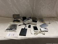 Full lot view showing assortment of electronics and accessories including phones, external hard drive, mouse, and packaging.
