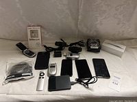 Full overview of all items showing multiple phones, the Apple iPhone box, charging cable, remote, webcam, and hard drives