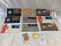 Full lot assembled on white cloth background showing all coins, first day covers, and commemorative envelopes in an organized arrangement.