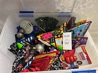 Full view of the plastic bin filled with dog accessories showing colorful bandanas, toys and leashes inside.