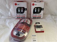 Two SIIG 8 ft 4K High Speed HDMI cables in retail packaging, one Rockfish 8 ft HDMI cable with cable clip in plastic packaging, and one SIIG HDMI coupler in retail box on white fabric backdrop.