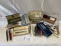 Wide view of pens including multiple boxed sets of Cross pens and many loose pens, some in original boxes.