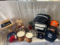 Full view of bundled items including hats, backpack, stuffed toys, sports memorabilia, and bongos.