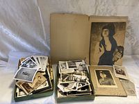 Overall view showing two trays filled with photos and an old book with a painted portrait on the cover.