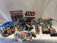 Overview photo of Lego Star Wars sets, books, assembled starship, loose mini-figures, and other Star Wars items on white cloth background
