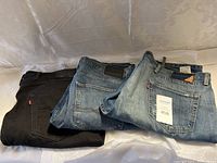 Three pairs of Levi's jeans: one black, one medium blue, and one light blue, all folded showing back pockets and labels.