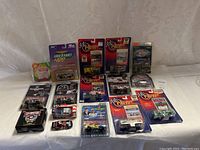 Full overview of 13 NASCAR collectible diecast cars and memorabilia items mostly featuring Dale Earnhardt in various packaging and blister packs arranged on white surface.