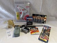 Full view of lot showing glue gun with glue sticks, battery charger, batteries, silver propeller item, small camera or camcorder, and pouch.