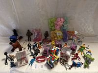 Wide shot of entire toy bundle showing plush, action figures, Rubik's cubes, and other toys.