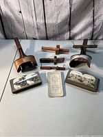Front view of two antique stereoscope viewers, two sets of stereoscopic slides, and various wooden parts laid out on table.