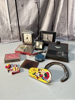 Lot of various vintage items including three clocks, card cases, leather money clip holder, ashtray, cigarette holder, toys and collectibles.