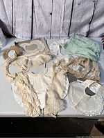 Overview of all antique lace pieces, small green fabric item, and dark tan hat spread out on table