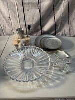 Overall view of lot items showing crystal bowl, bar stoppers, bar helper set with jigger, muddler on wooden base, textured plates, leaf plate, and angel figurine.