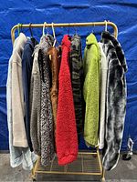 Full rack showing all 8 hanging outerwear and fleece pieces in different colors and textures.