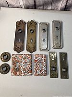 Photo showing all the ceramic light switch covers along with metal hardware plates arranged on a white surface.