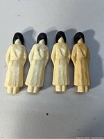 Four Native American style plastic dolls standing upright, showing back side.