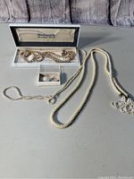 Overview of lot displaying multiple pearl necklaces and a small box with pearl earrings arranged on table.